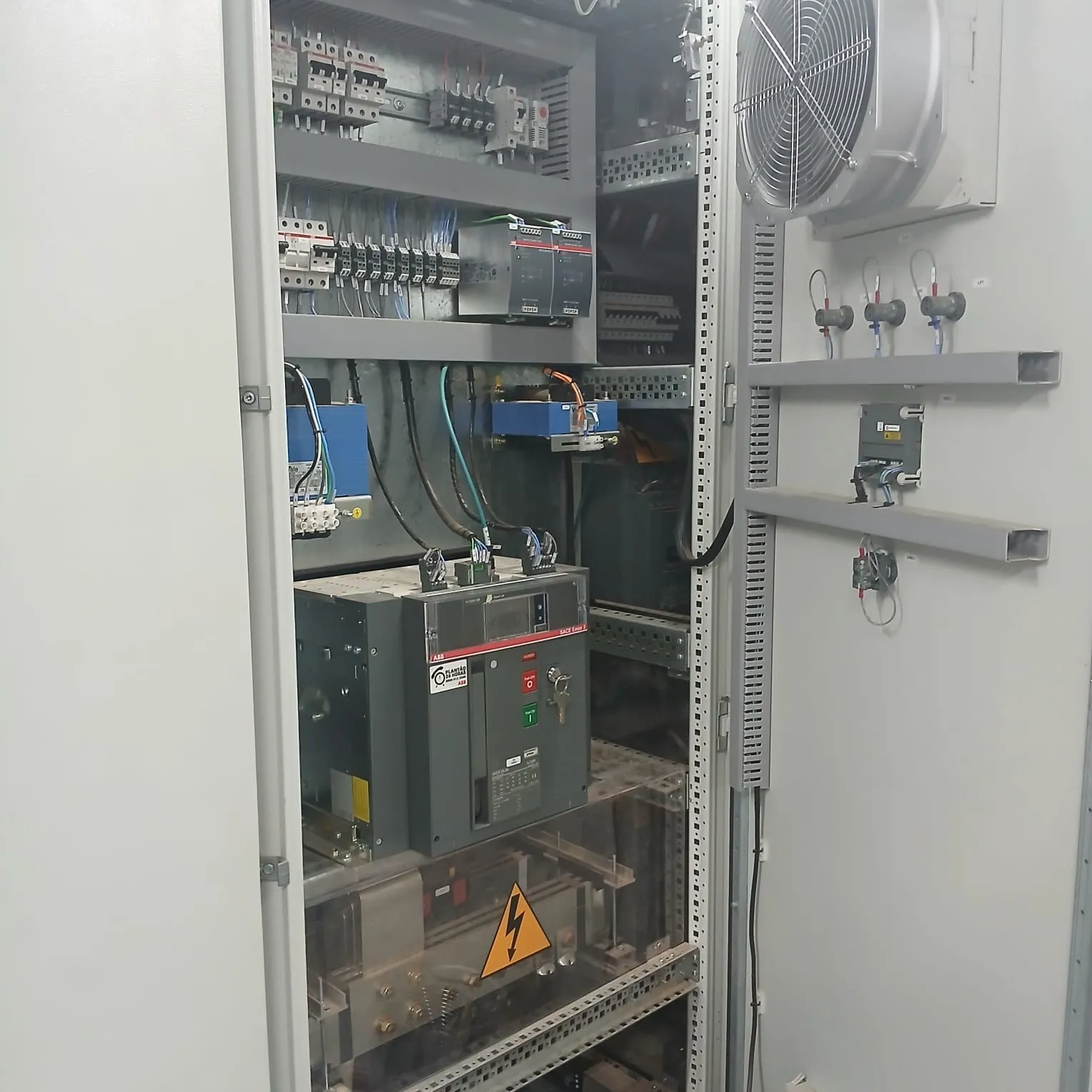 Disjuntor de ar motorizado ABB SACE Emax 2 dentro de um quadro geral de grande porte, com exaustor instalado na porta do painel.