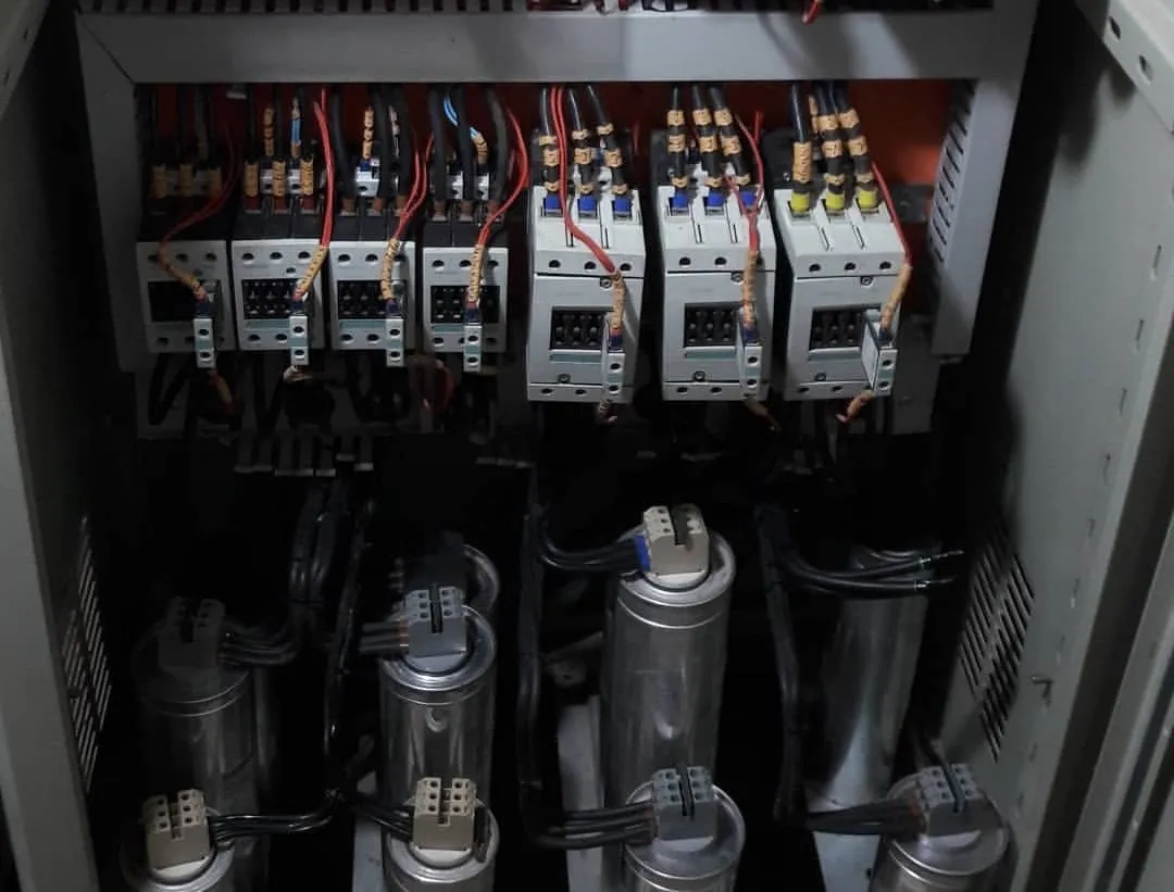 Interior de banco de capacitores com contatores, cabeamento e células capacitivas.