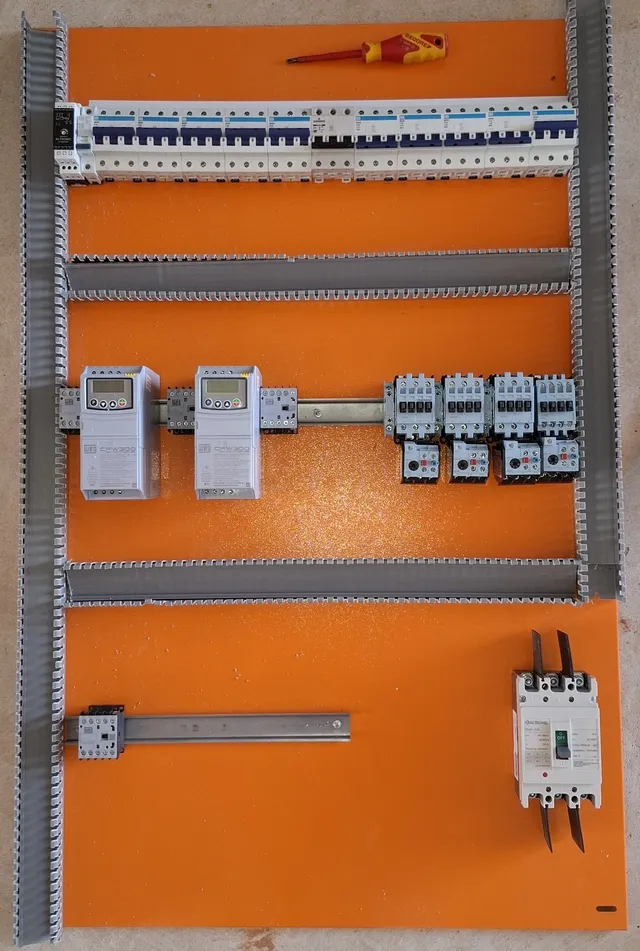 Placa de montagem de painel elétrico apoiada no piso, com uma régua de disjuntores, dois inversores de frequência WEG CFW300 e quatro contatores Altronic com relés térmicos fixados no trilho, ainda sem fiação.