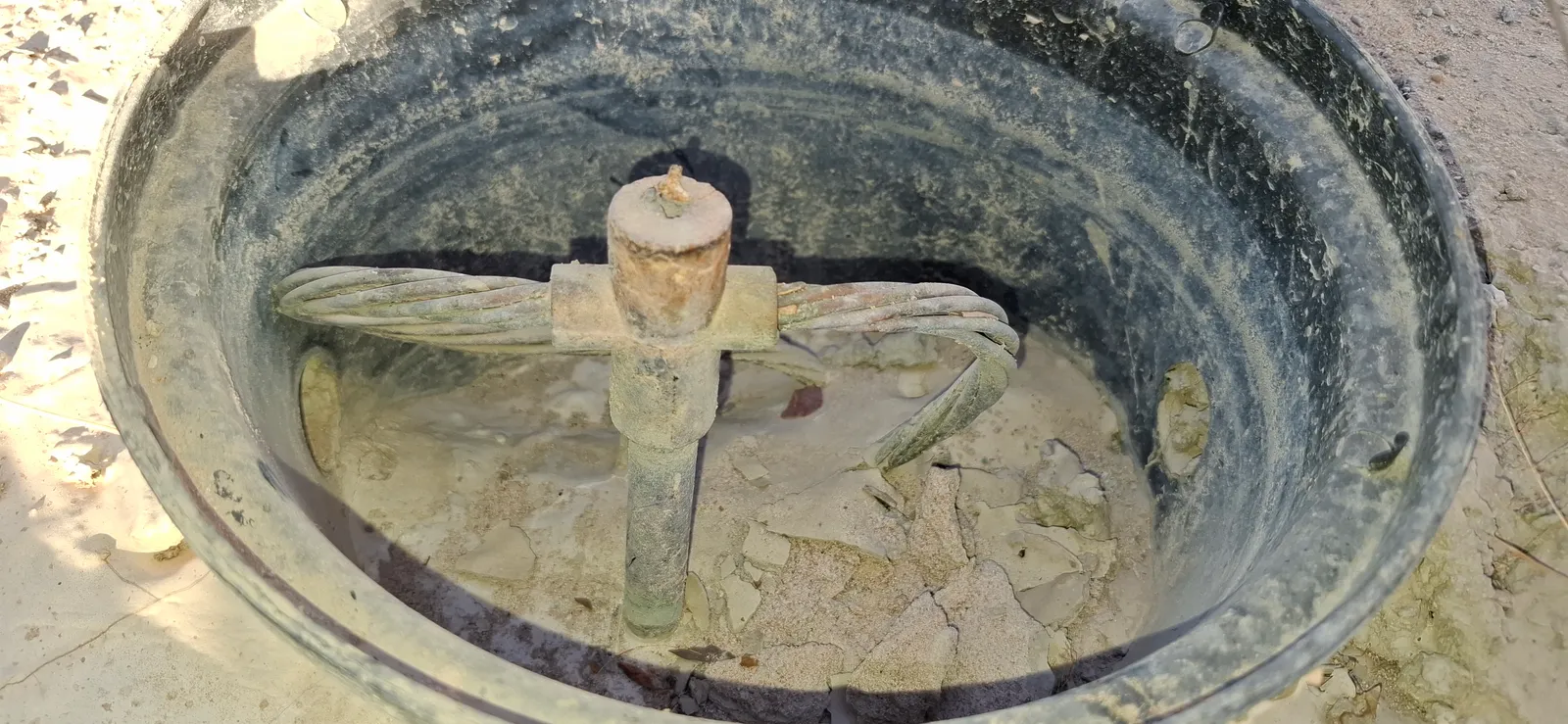 Caixa de inspeção de aterramento aberta, mostrando a haste, o conector de medição e o cabo de cobre nu conectado.